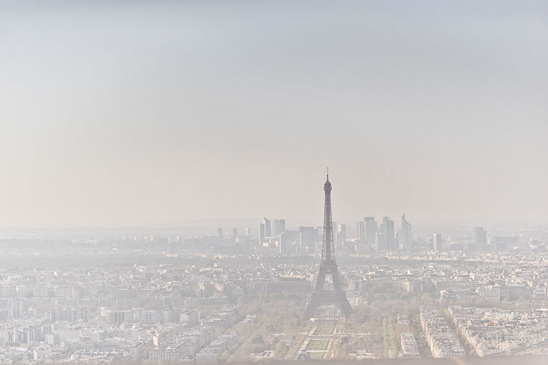 Looking out over Paris skyline, through the haze and polution, the eiffle tower is visable in the distance.