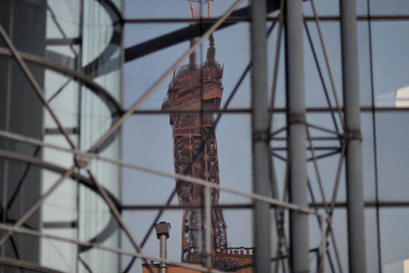 An image of the Eiffel Tower reflected ion the glass of a building